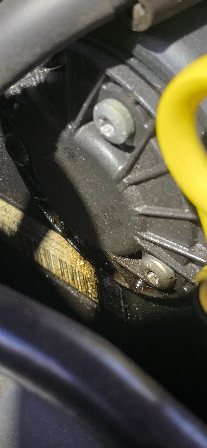 Oily residue around the upper and lower timing cover area of a VW Tiguan engine.