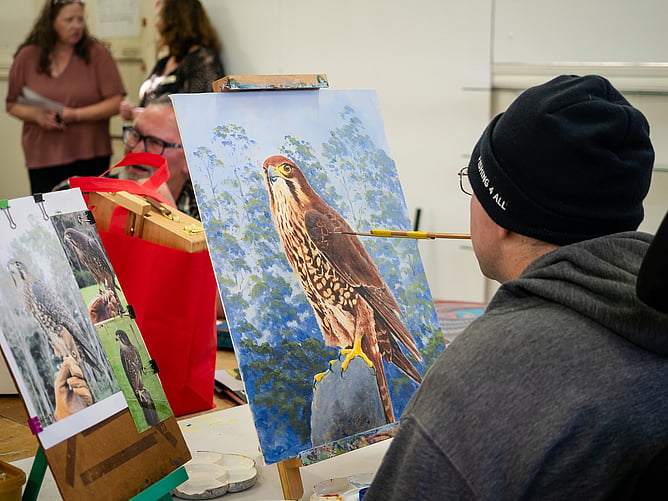 Artist Kerrin Tilley works on a painting of a falcon.