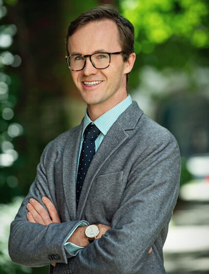 Man in a suit and tie; he is smiling at the camera.
