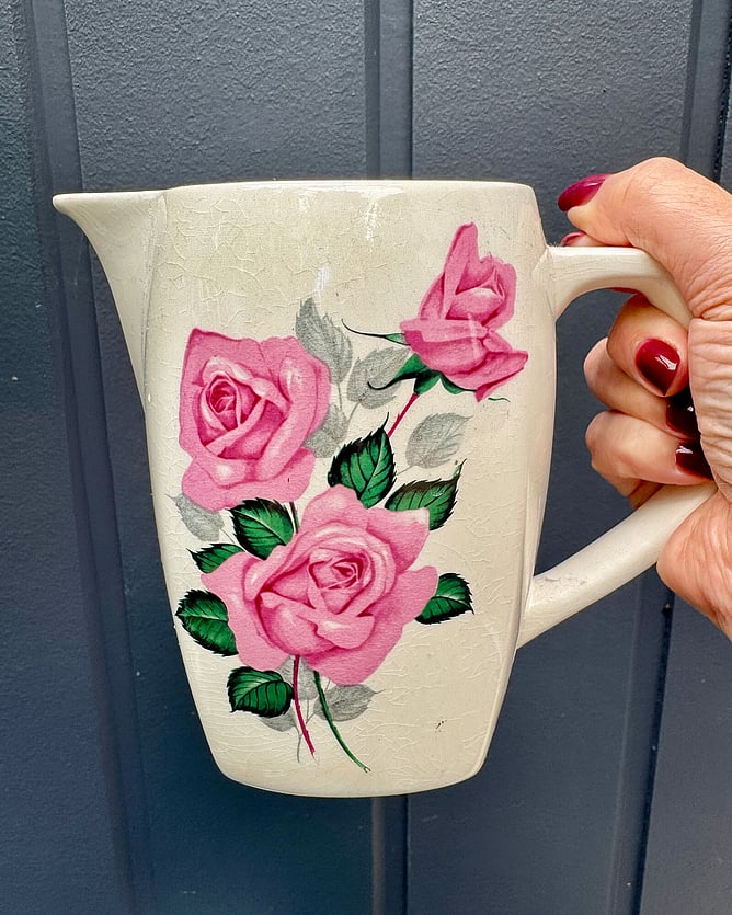 New Zealand artist Anna Mollekin holding a vintage Crown Lynn jug in the Fashion Rose pattern, No. 750, featuring detailed floral designs and rich colours.