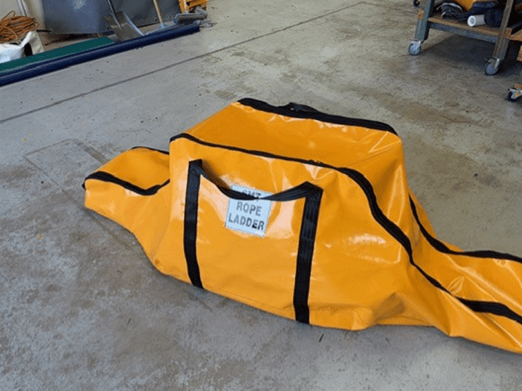 Orange rope ladder bag with sling-style handles on a workshop floor