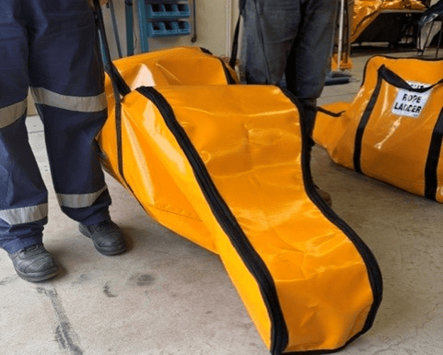 Two people carrying an orange rope ladder bag by its handles