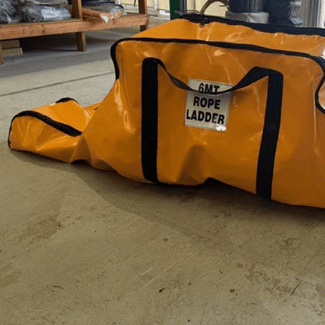 Orange rope ladder bag with sling-style handles on a workshop floor