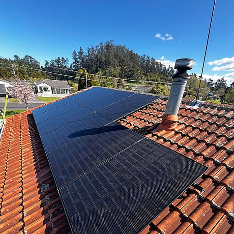 Black panel array on a tiled roof in Waihi, on a clear spring day