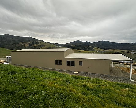 A finished Henley shed home on the hills above Dunedin, long single-level cladding with a carport at the end