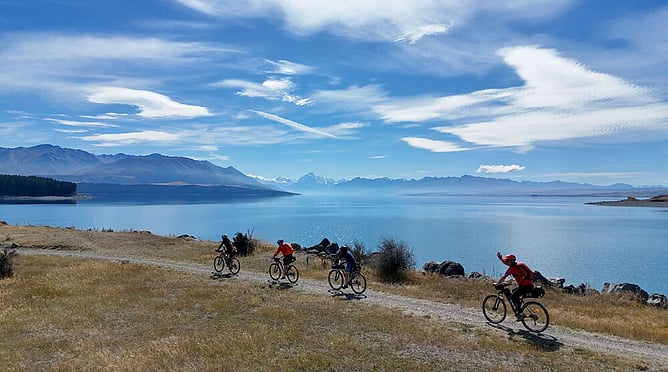 Cyclists on a self-guided South Island bike tour riding the Alps 2 Ocean trail beside Lake Pukaki