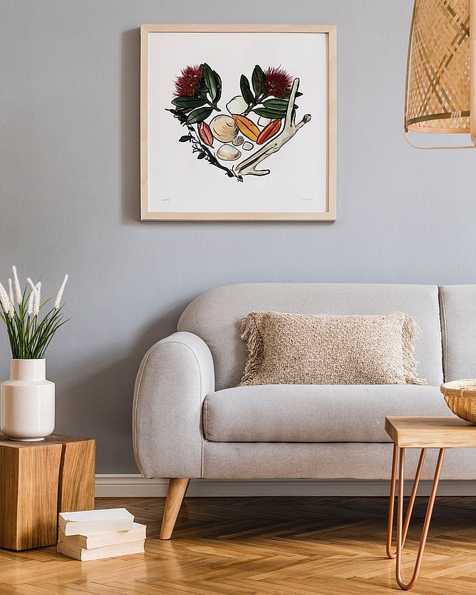 Sandy Bay art print with pōhutukawa, shells and driftwood framed above a sofa