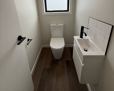 Refreshed powder room with a wall-hung vanity, black tapware and a new toilet