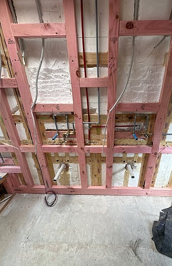 Vanity wall before the renovation, opened up to the framing with new pipework