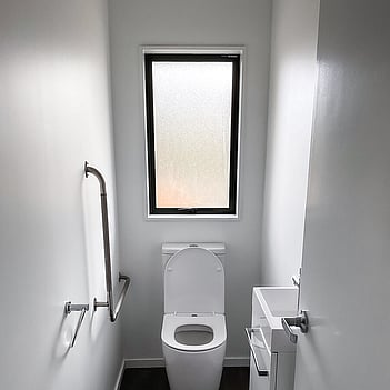 Accessible toilet suite with grab rails in a small bathroom