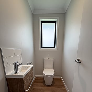 Powder room with a new toilet and timber vanity