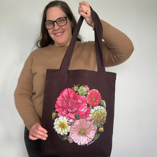 Anna Mollekin holding her Lucy&rsquo;s Blooms flower art tote bag, a New Zealand gift to pack for Kiwis overseas
