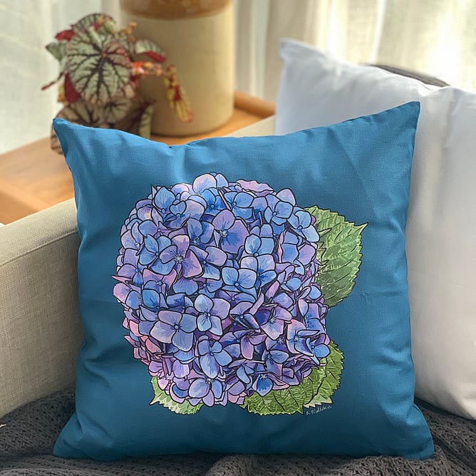 Hydrangea Harmony cotton cushion cover by NZ artist Anna Mollekin on a sofa, a small gift that packs flat
