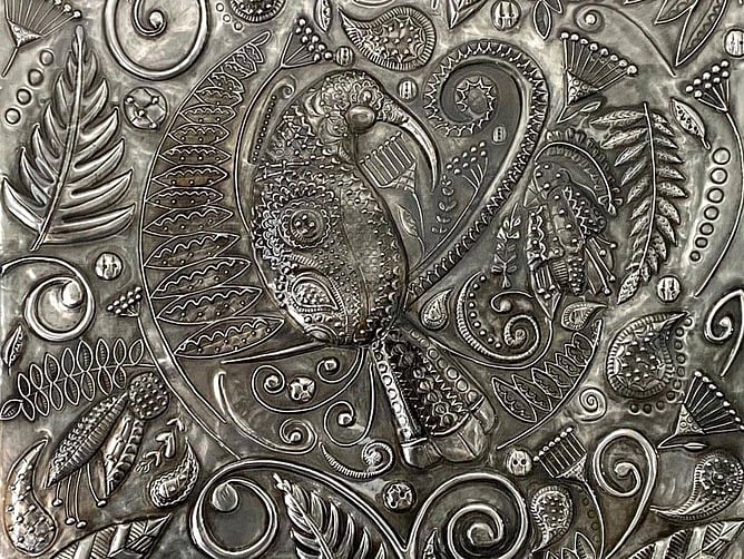 Close-up of the huia and lace patterns hand-embossed in pewter wall art by Ninette Kruger and Anna Mollekin