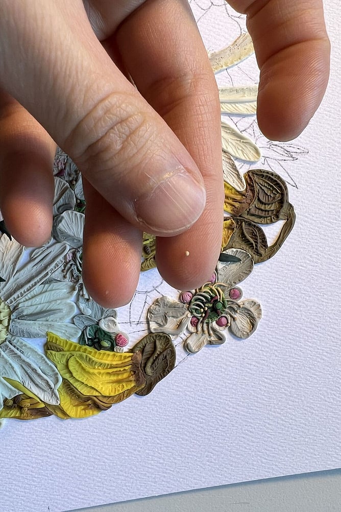 Emy Oikawa placing tiny pieces of clay by hand