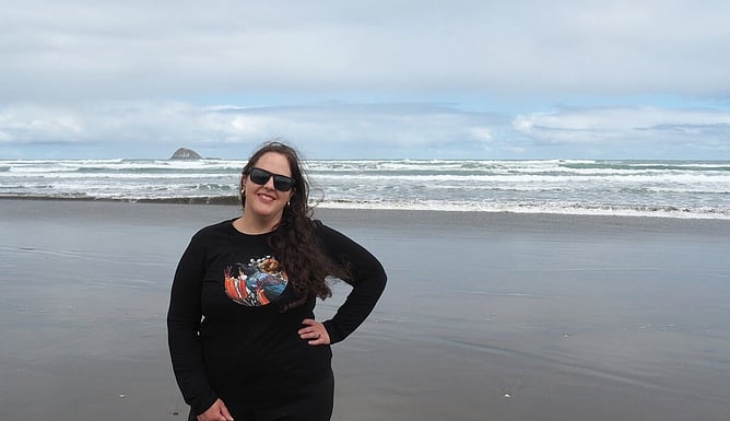 Auckland artist Anna Mollekin at Muriwai Beach wearing her tūī artwork
