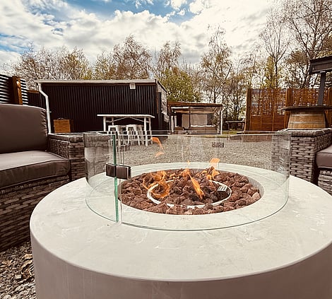 Woodland Courtyard featuring comfortable outdoor lounge seating, fire pit, gravel grounds, bar learners and peaceful surrounding trees