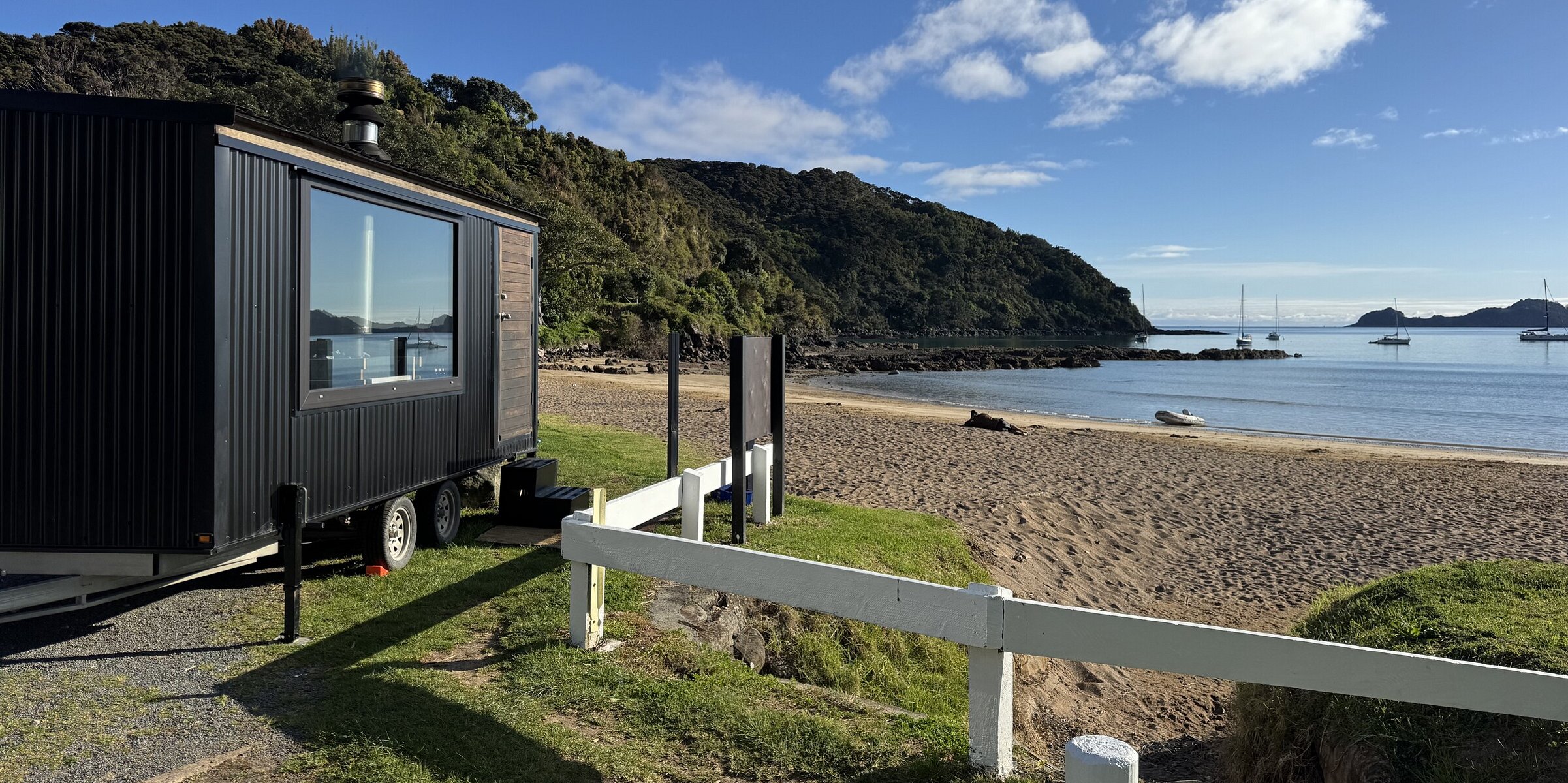 Traditional wood-fired barrel sauna sitting directly on the sand at Long Beach in Russell, Bay of Islands