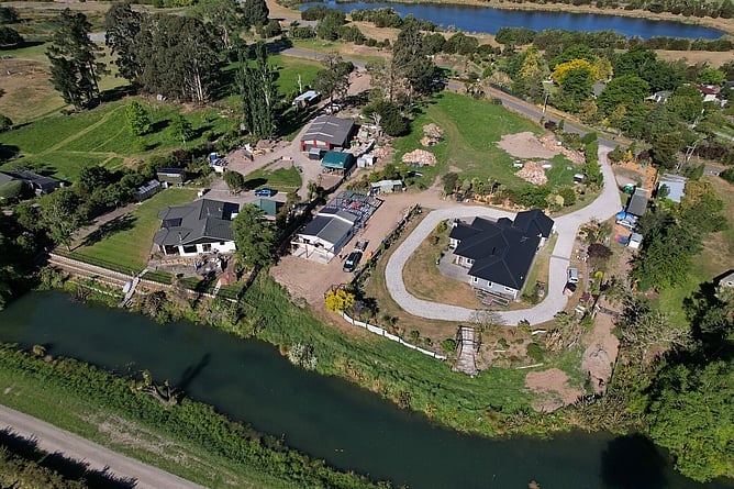 Aerial view of the Kaiapoi property beside the river, with the new granny flat and garage taking shape between the existing homes