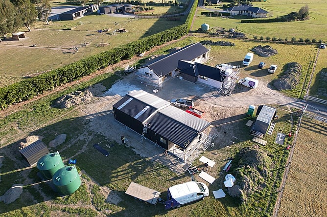 Aerial view of the Rural Darfield build in progress: the main house under scaffolding, the black Twizel minor dwelling being clad, water tanks and the fleet on site