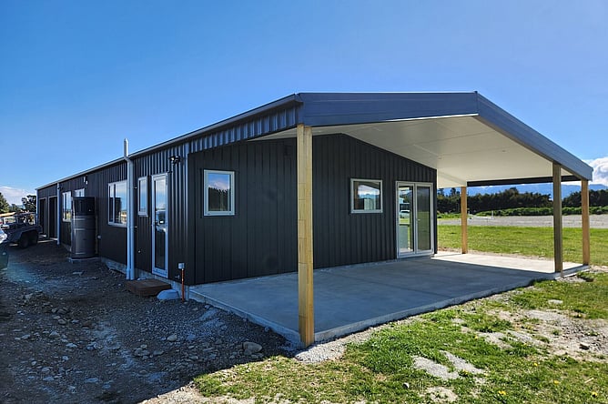 The finished black shed home in Oxford with its timber-post verandah and concrete patio