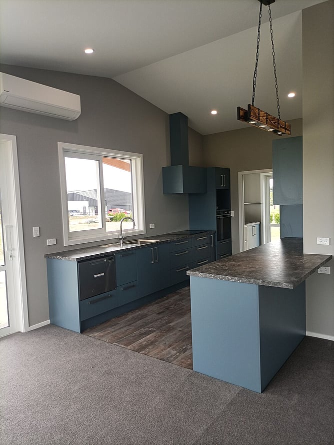 Blue kitchen with a stone-look benchtop and a timber beam pendant light