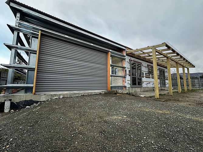 The steel-framed garage end with its roller door fitted, the house still wrapped and the verandah pergola framed up