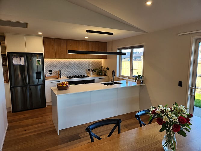 The kitchen island and dining table, with the fridge and pantry tucked around the corner