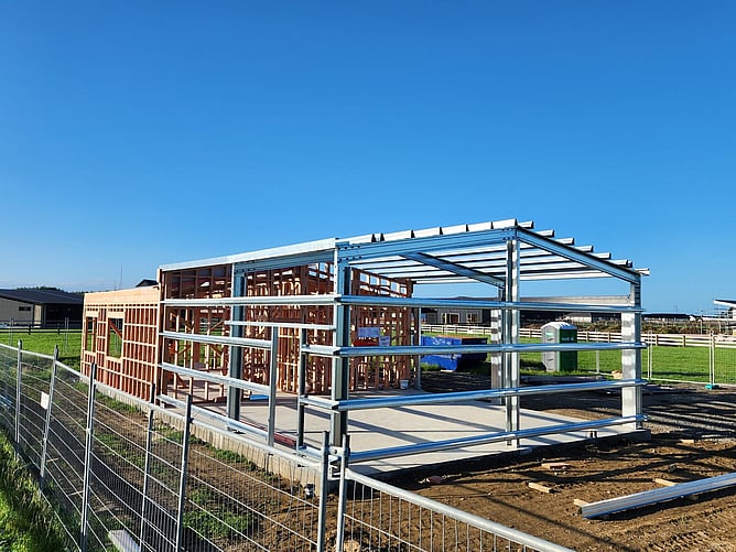 Steel portal frames and timber framing for the Lincoln Karapiro going up on the slab, with the empty section around it