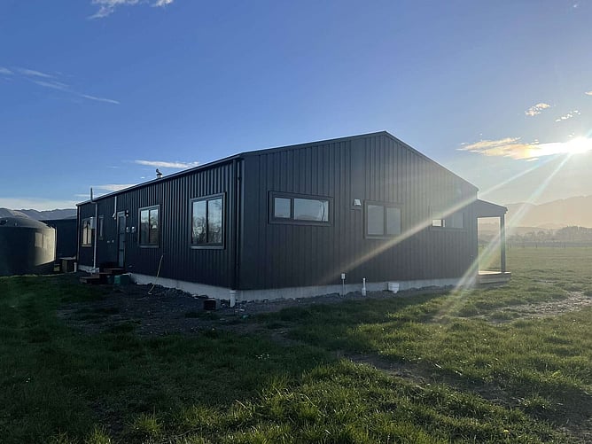 The steel-clad back of the Kaikoura home at sunrise, with the water tank and the Kaikoura hills behind