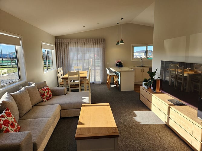 The lounge and dining area of the Darfield showhome, open plan through to the kitchen, with sun coming through the sliders