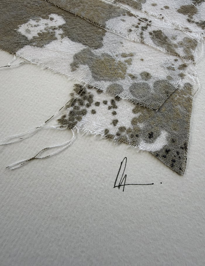 close-up image of soft white fabriano surface texture, layered repurposed pale cream cotton fragments blotted with green-grey and black acrylic, visible weave texture, soft frayed edges and handwritten signature directly beneath the artwork