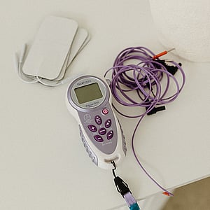 Picture of an Elle 2 TENS unit, with electrodes and pads