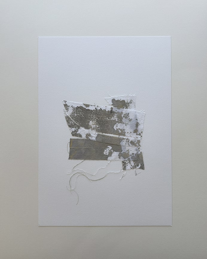 full image of a layered collage on soft white fabriano, showing repurposed pale cream cotton fragments blotted with green-grey and black acrylic, visible weave texture, soft frayed edges and handwritten signature directly beneath the artwork