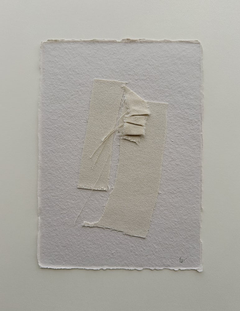 full image of a layered collage on handmade sand-toned, deckled-edged cotton rag paper showing three repurposed oat-toned cotton fragments, with one small fragment hand-stitched into gentle folds and secured on top, visible weave texture, soft frayed edges and downward hanging threads, with handwritten signature in lower right corner