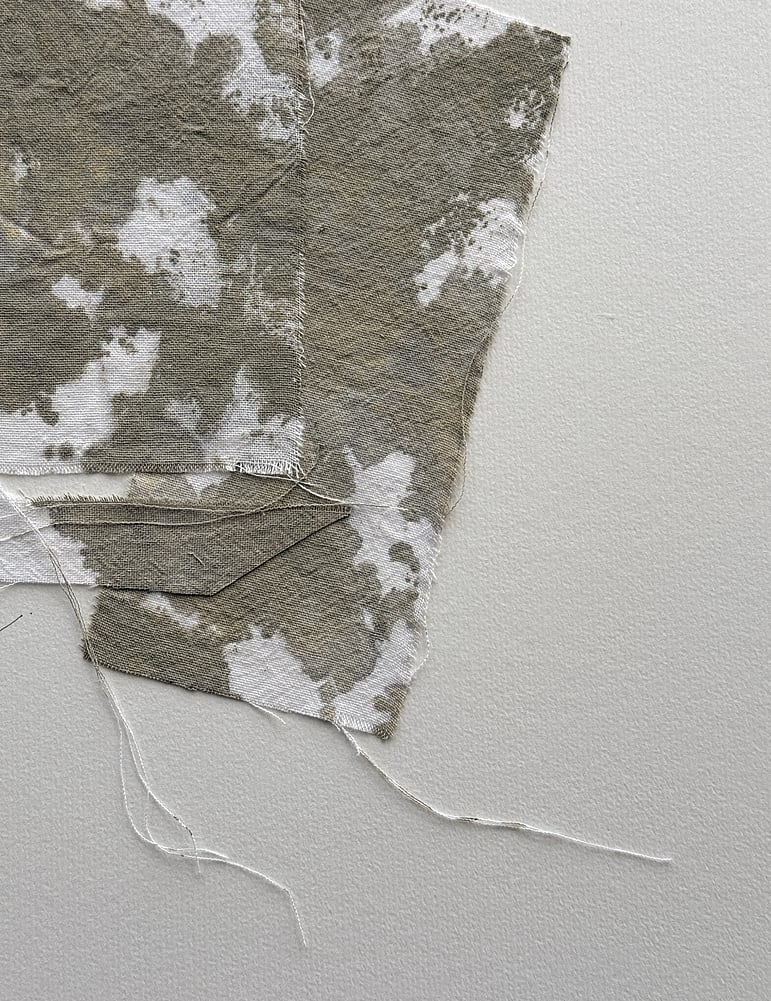 detail image of layered repurposed pale oat-toned cotton fragments hand-painted with green-grey and raw sienna acrylic, showing visible weave texture, hanging threads and soft frayed edges 