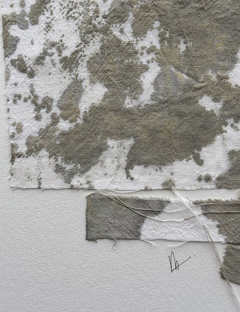close-up image of soft white fabriano surface texture, layered repurposed pale oat-toned cotton fragments hand-painted with green-grey and raw sienna acrylic, visible weave texture, hanging threads, soft frayed edges and handwritten signature directly beneath the artwork