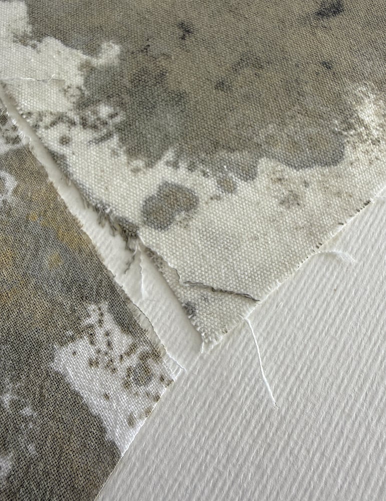 detail image of layered repurposed pale oat-toned cotton fragments hand-painted with green-grey and raw sienna acrylic, showing visible weave texture and soft frayed edges 