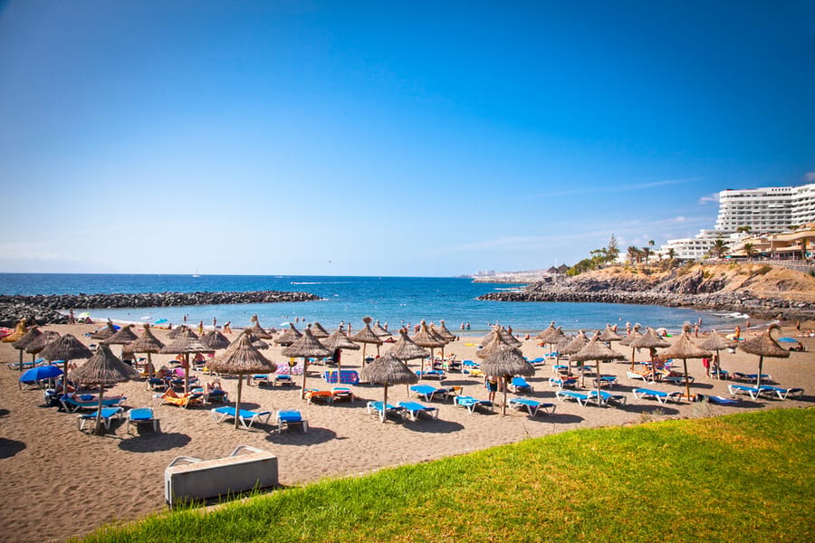 Beach with straw parasols and sunbeds in Costa Adeje, Tenerife