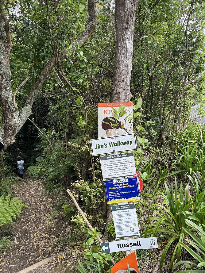 Trailhead sign for Jim's Walkway in Russell showcasing the Kiwi habitat warning and Golden Foot Walking Awards 2022 badge on a tree